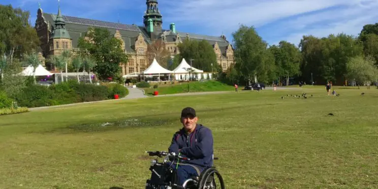 Un usuario de silla de ruedas en una colina con un castillo al fondo en un día soleado.