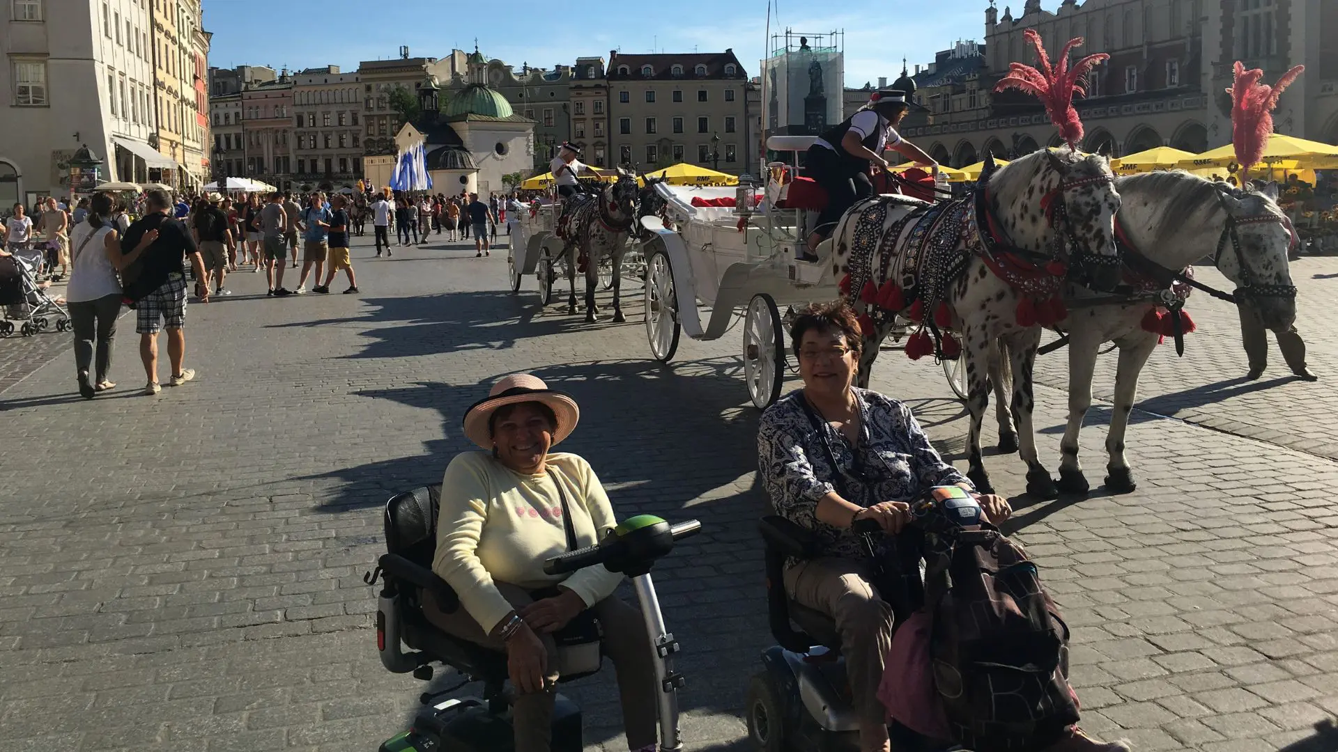 Dos viajeras en silla de ruedas disfrutando de Cracovia con un carruaje detrás