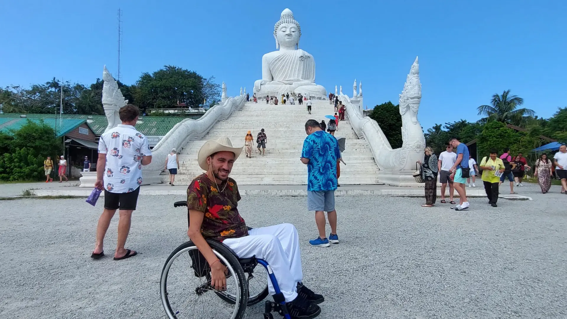 Usuario de silla de ruedas en un templo en Tailandia, al fondo se puede ver una estatua de un Buda blanco