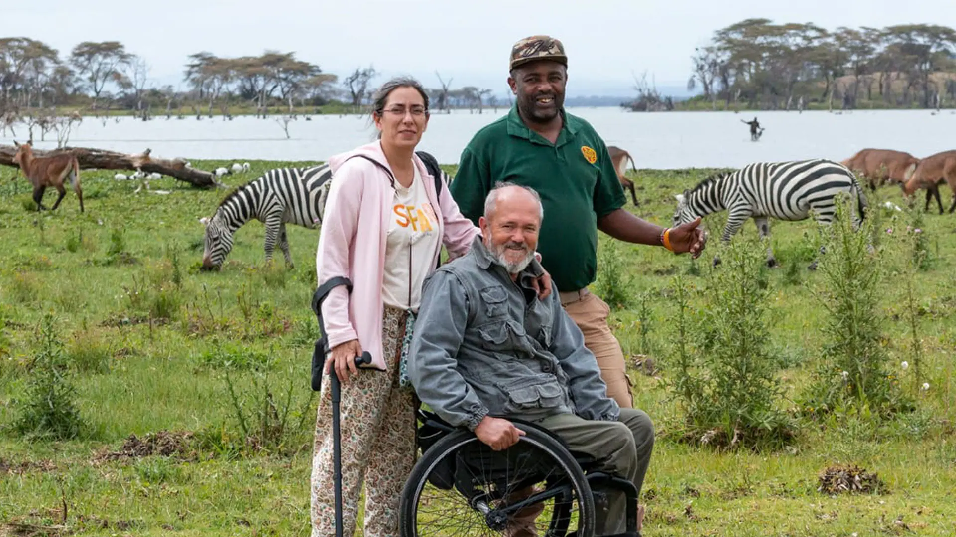 Una persona con discapacidad en un viaje adaptado a Kenia junto a su esposa y un guía en un tour accesible en un safari