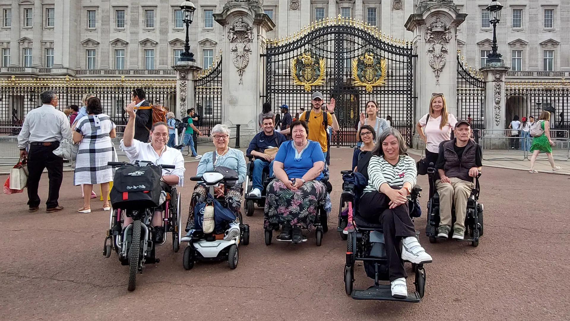 Un grupo de usuarios de silla de ruedas en un viaje adaptado para personas con discapacidad a Londres frente al palacio de Buckingham.
