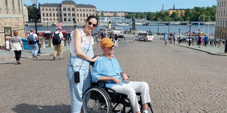 Una pareja en Estocolmo. Él es usuario de silla de ruedas. Al fondo se ven el río y edificios históricos de la ciudad