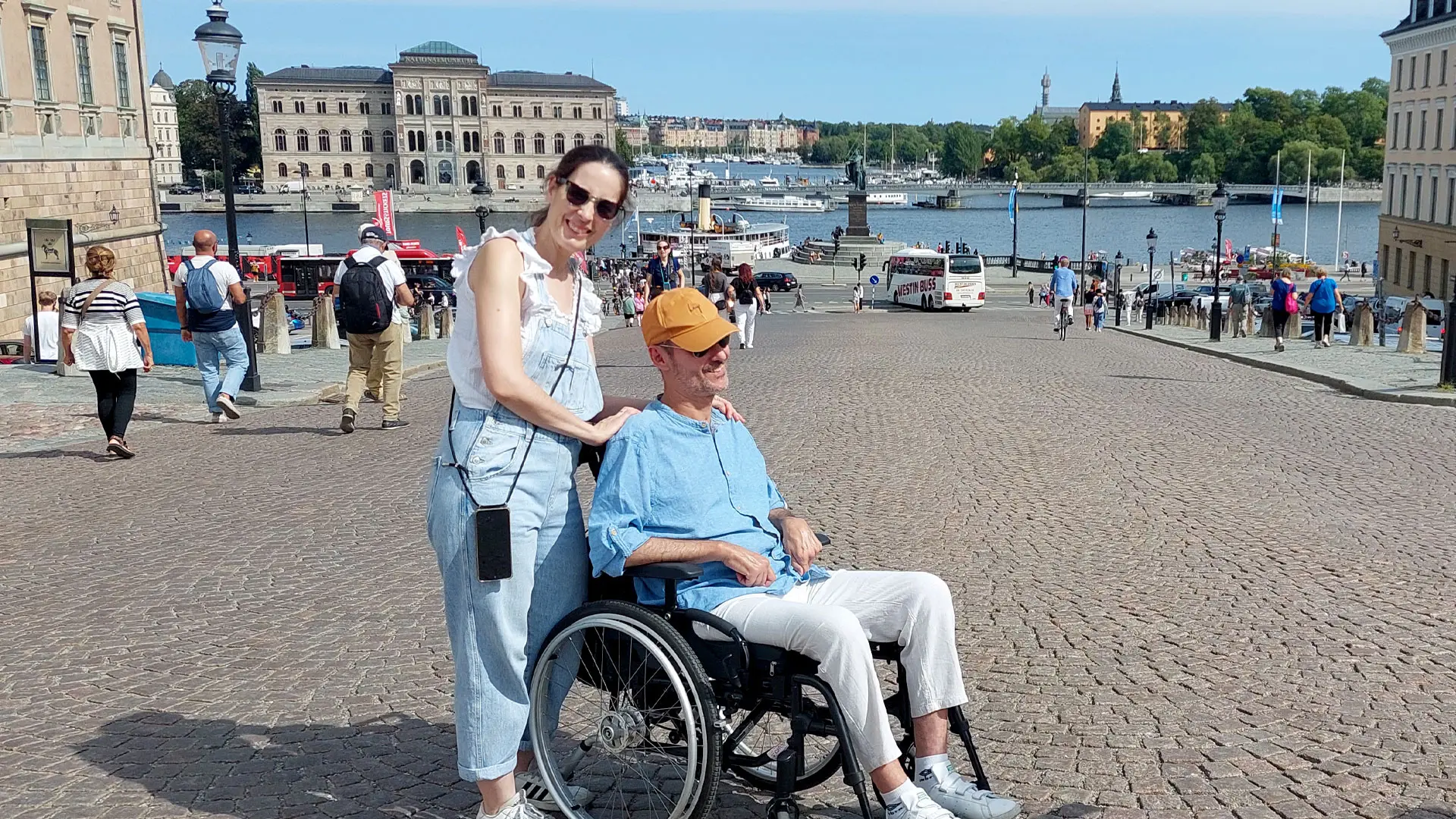Una pareja en Estocolmo. Él es usuario de silla de ruedas. Al fondo se ven el río y edificios históricos de la ciudad