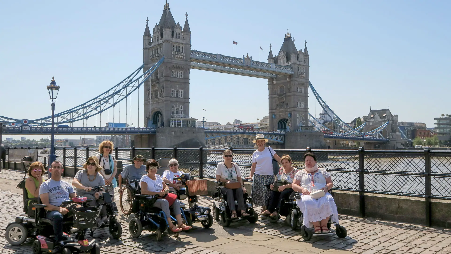Grupo de usuarios de silla de ruedas posando frente al London Bridge en un día soleado. Londres en silla de ruedas.