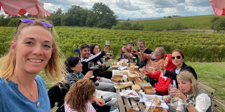 Imagen de un grupo de personas entre ellos, algunos usuarios de silla de ruedas, brindando y comiendo junto a un viñedo en la Tostaca.