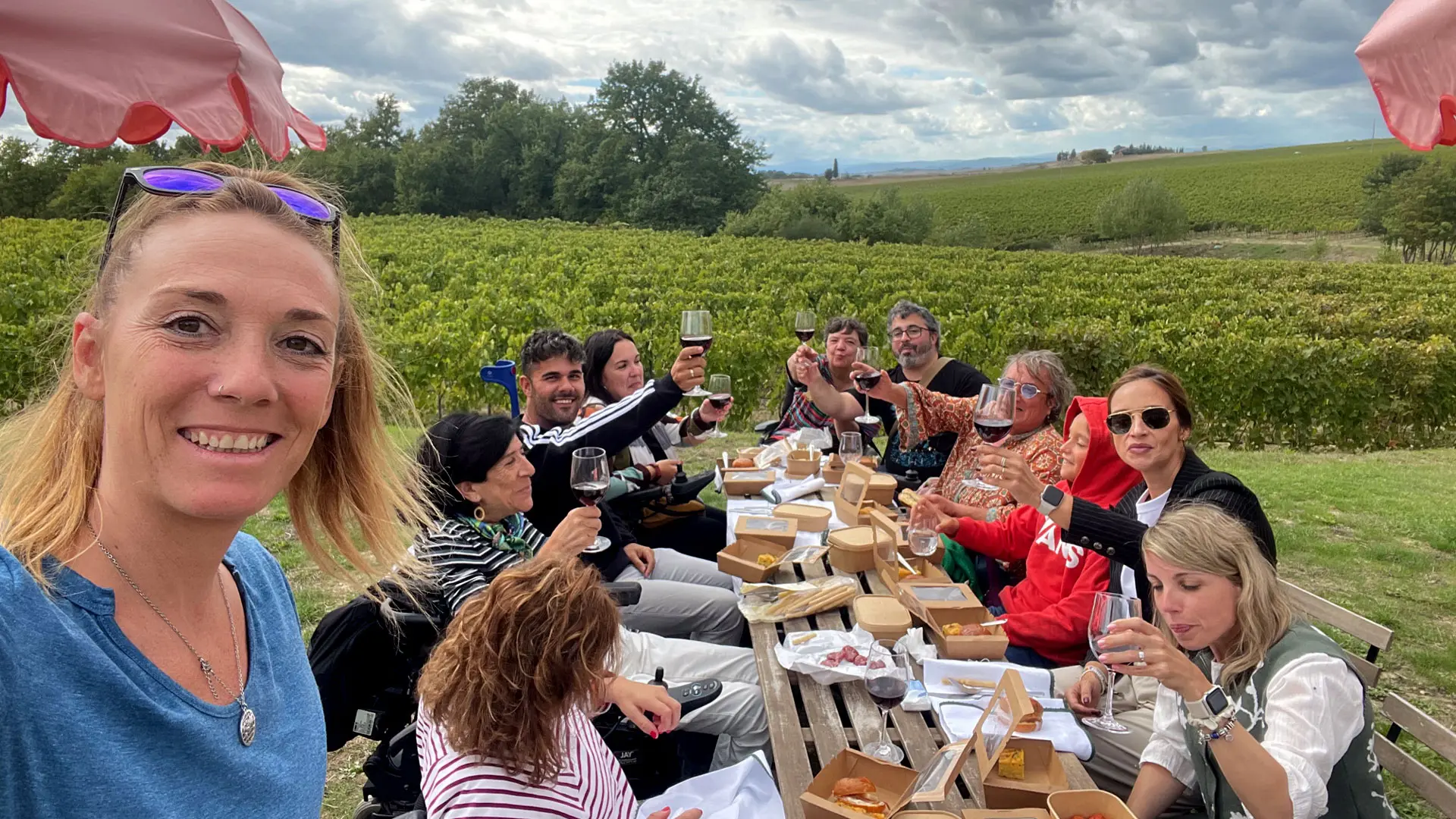Imagen de un grupo de personas entre ellos, algunos usuarios de silla de ruedas, brindando y comiendo junto a un viñedo en la Tostaca.