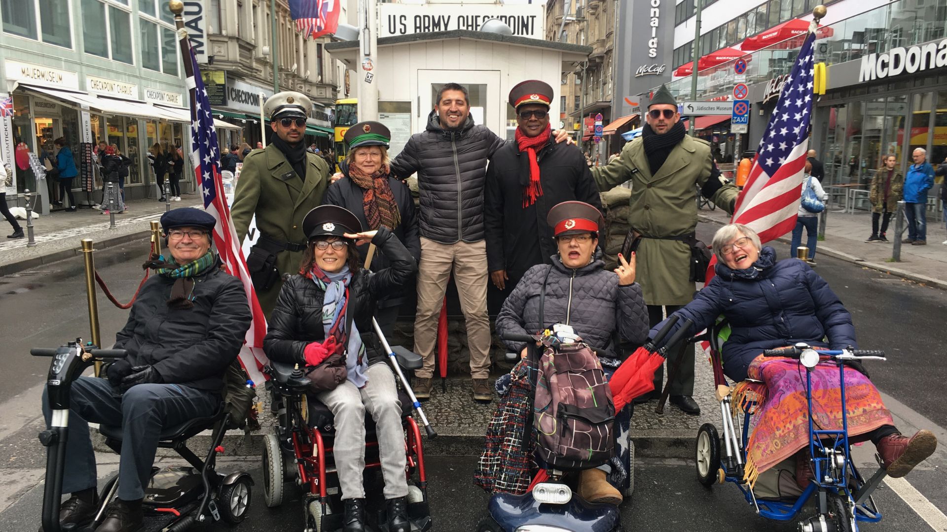 Un grupo de usuarias de silla de ruedas junto a los militares en el check point charlie en Berlin