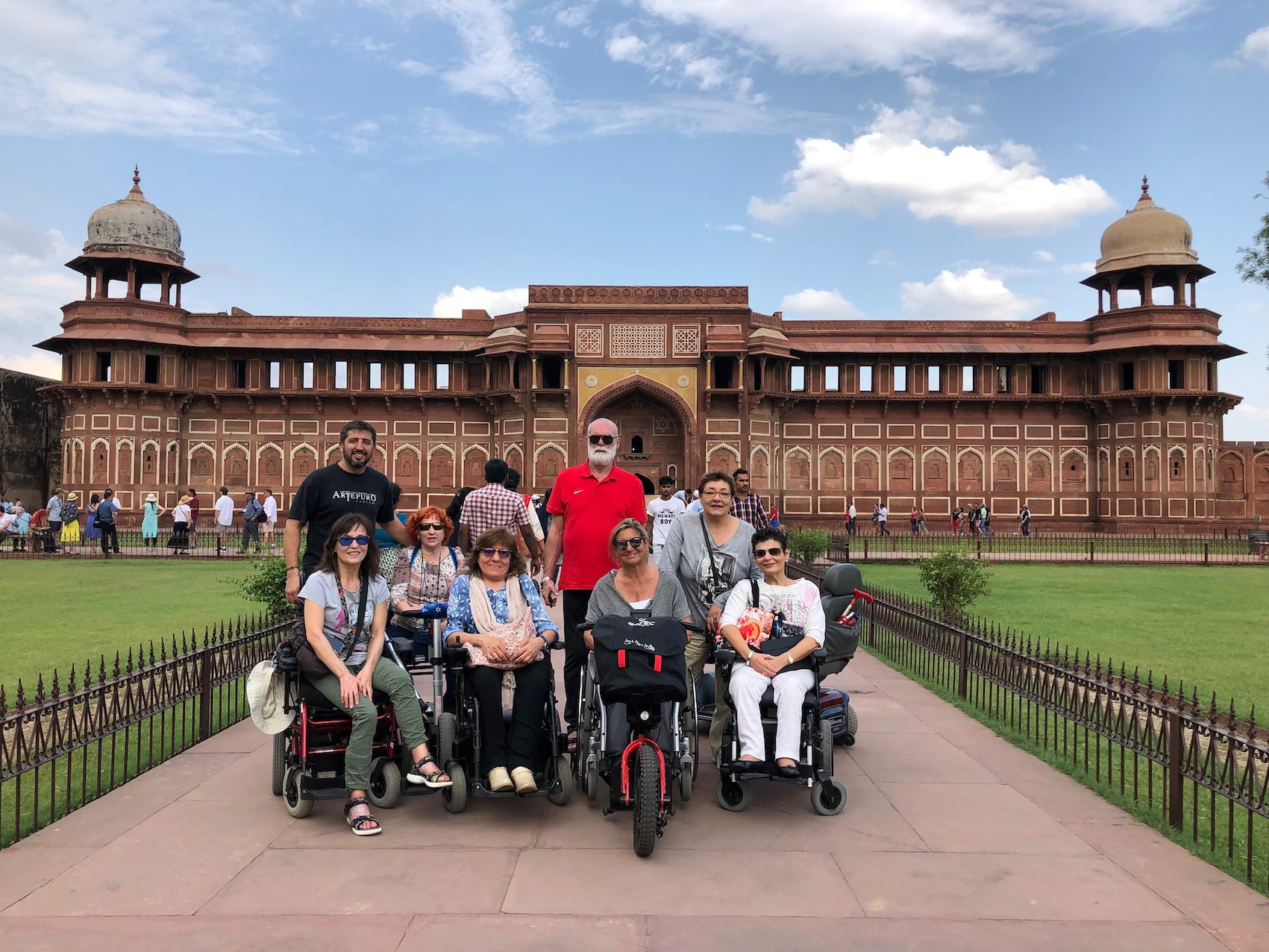 Un grupo de usuarios de silla de ruedas en un viaje adaptado a la india, al fondo se ve el fuerte rojo.