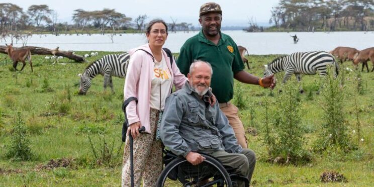 Una persona con discapacidad en un viaje adaptado a Kenia junto a su esposa y un guía en un tour accesible en un safari