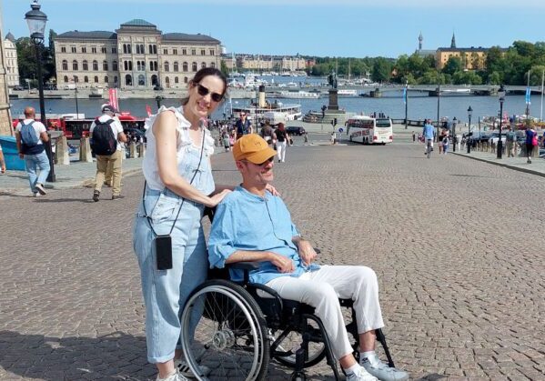 Una pareja en Estocolmo. Él es usuario de silla de ruedas. Al fondo se ven el río y edificios históricos de la ciudad