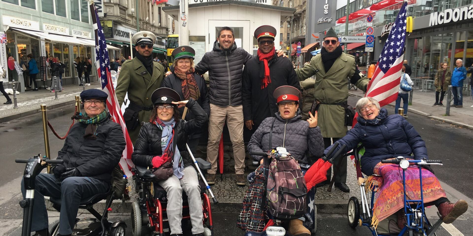 Un grupo de usuarias de silla de ruedas junto a los militares en el check point charlie en Berlin