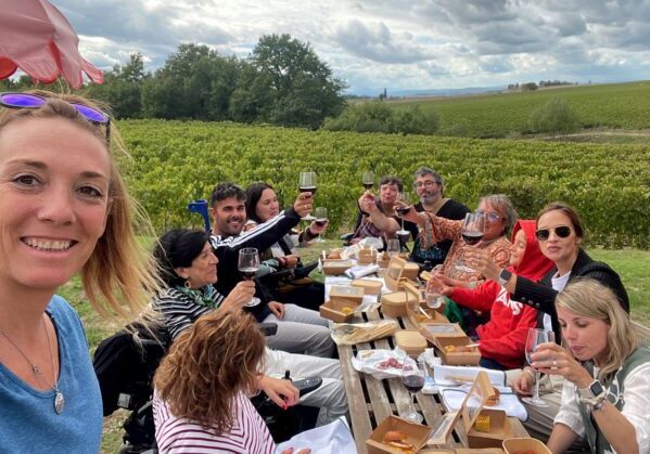 Imagen de un grupo de personas entre ellos, algunos usuarios de silla de ruedas, brindando y comiendo junto a un viñedo en la Tostaca.