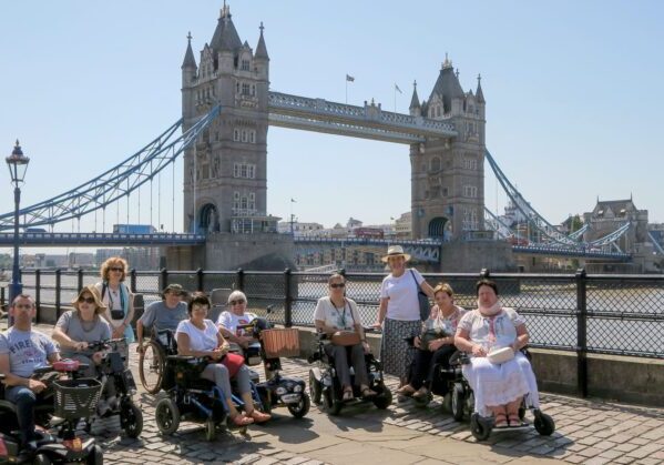 Grupo de usuarios de silla de ruedas posando frente al London Bridge en un día soleado. Londres en silla de ruedas.