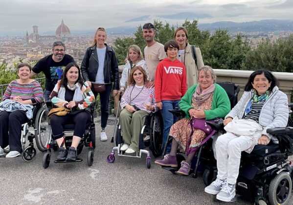 Un grupo de viajeros y viajeras usuarias de silla de ruedas en un viaje adaptado en grupo a Florencia. Al fondo se ve la ciudad de Florencia y la cúpula de la catedral.