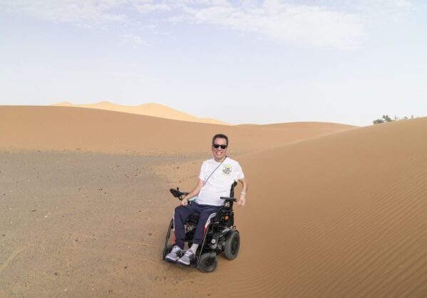 Un usuario de silla de ruedas en medio de las dunas en un viaje adaptado a Marruecos